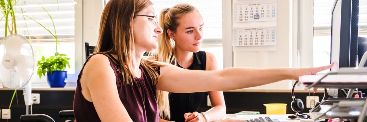 Zwei junge Frauen arbeiten zusammen an einem PC.